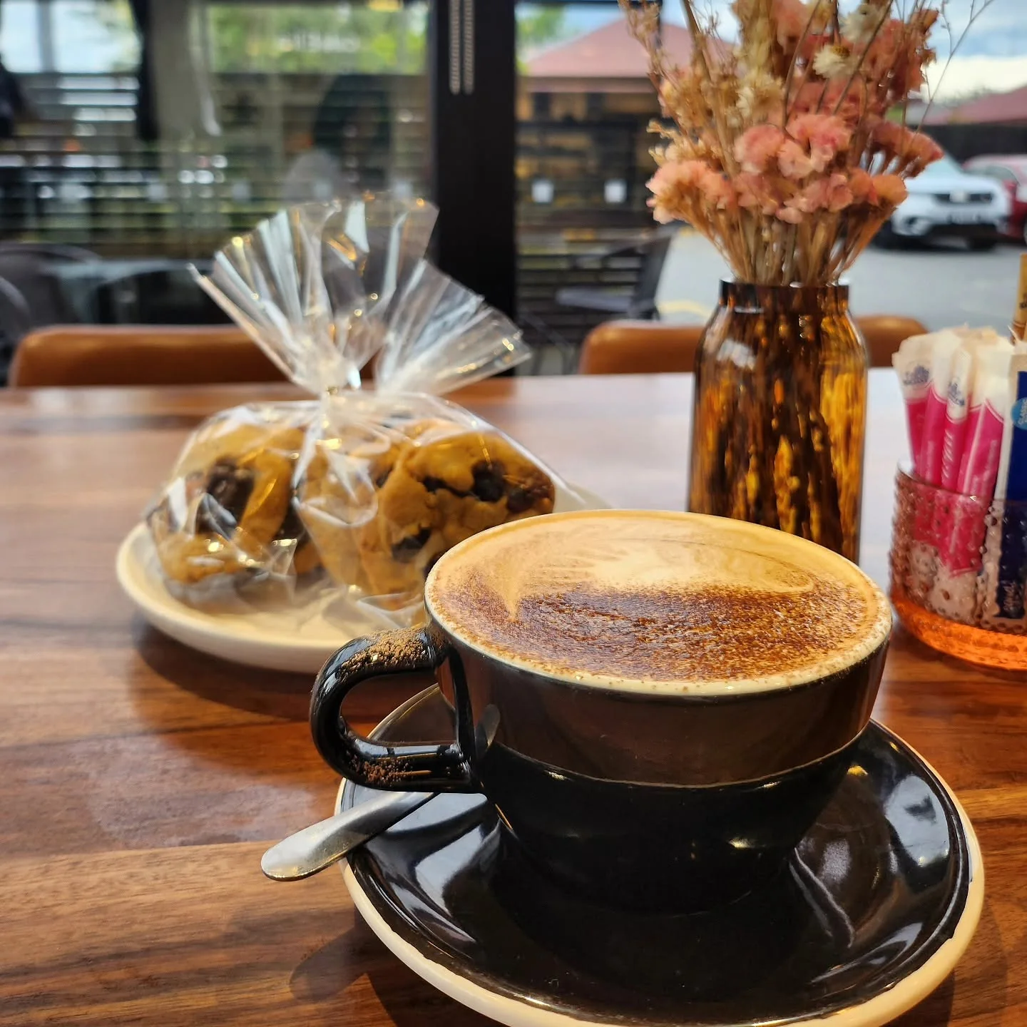 A cup of coffee and a slice of cake beside the Cafe Elia window