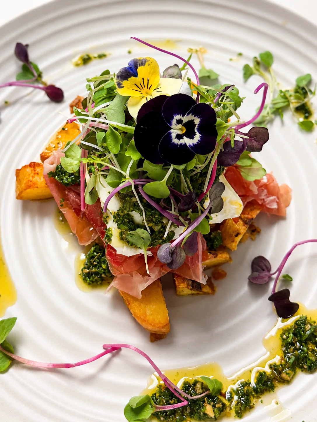 A Cafe Elia savoury brunch plate with prosciutto, greens and edible flowers