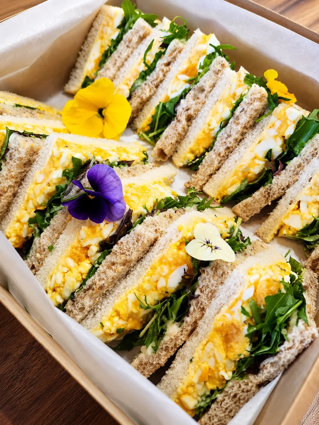 Freshly prepared Cafe Elia egg and rocket sandwiches with edible flowers